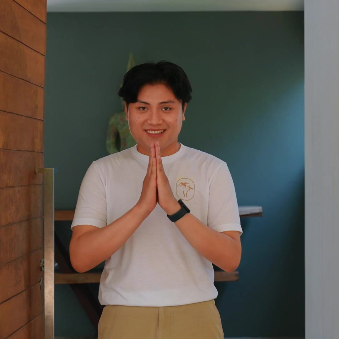 A Staylar team member in a Staylar T-shirt greeting with a wai at the villa door