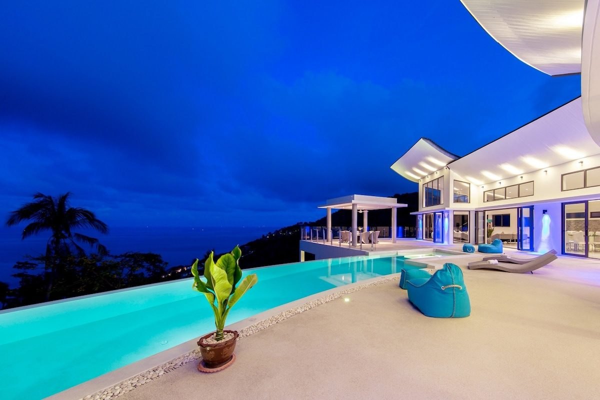 Villa Maeva lit at dusk above its infinity pool